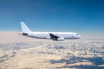 White modern aircraft flying over snow covered mountains