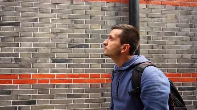 Candid of a tourist feeling a grey brick shikumen wall in Xintiandi to connect with the French Concession history. Shanghai, China