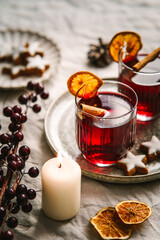 Zwei Gläser Glühwein mit Zimt und Orange auf einem Serviertablett. Modern, Kerze, Weihnachten.