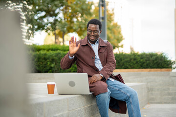 African american man waving at laptop during video call