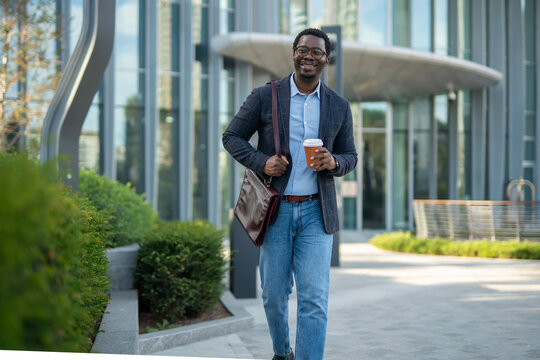 Smiling african american businessman walking with coffee in city