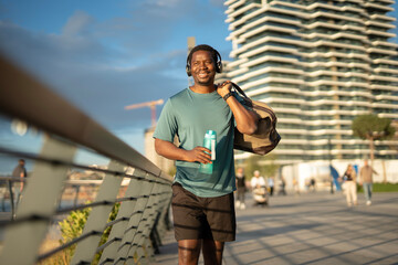 Happy man walking carrying gym bag and water bottle