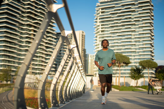 African american man jogging in urban city environment - Powered by Adobe