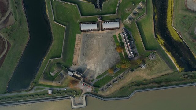 Aerial view of Tilbury Fort, a historic coastal defense, reveals its star shape, surrounded by water, with green grass and aged buildings, Tilbury, England, United Kingdom.