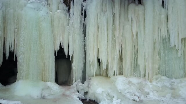 Frozen thick icicles at the entrance of Eben Ice Caves seen from outside, snow-covered ground in foreground. USA, zoom in