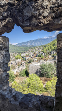 A portrait view of the ghost town of Kayakoy through the window of a ruined house