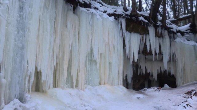 Massive frozen wall of vertical icicles cascading from a rocky ledge above the Eben Ice Caves in Michigan.