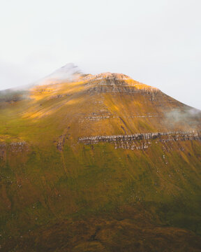 Aerial view of Sl&Atilde;&brvbar;ttaratindur peak, a majestic crown of rugged beauty, kissed by golden sunlight and shrouded in ethereal mist, Sl&Atilde;&brvbar;ttaratindur, Eysturoy, Faroe Islands.