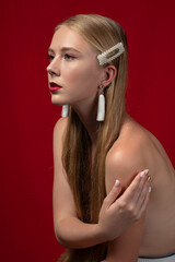 Fashion photo of a blonde girl with long hair on a red background