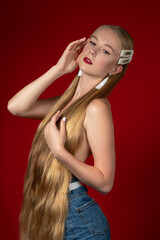 Fashion photo of a blonde girl with long hair on a red background