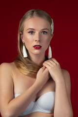 Fashion photo of a blonde girl with long hair on a red background