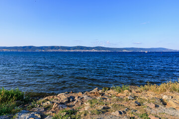 Serene coastal landscape with rocky shore and calm blue sea on sunny day