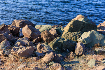 Rocky shoreline with blue water and sunlit rocks by the sea