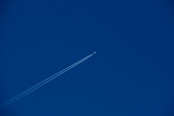 Airplane in the blue sky with white contrail.