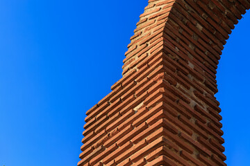 Red brick architectural arch against clear blue sky
