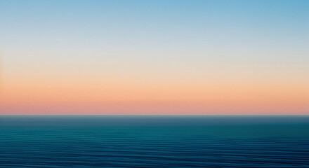 Calm ocean view at sunset with gradient sky from blue to orange and pink horizon line visible afar
