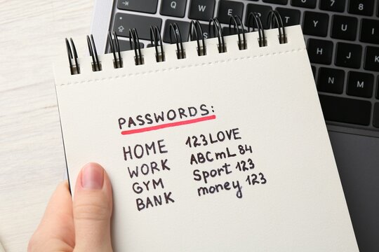 Woman holding notebook different passwords at table, closeup