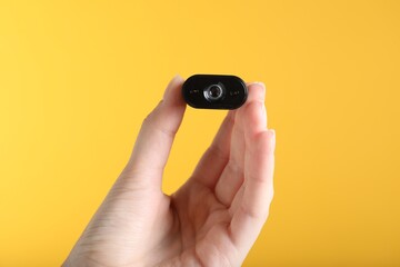 Woman with hidden spy camera on yellow background, closeup