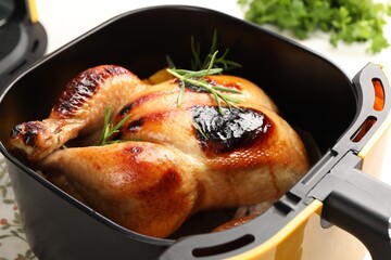 Tasty grilled chicken with rosemary in air fryer on table, closeup