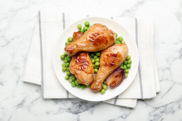 Grilled chicken drumsticks, green peas and onion on white marble table, top view