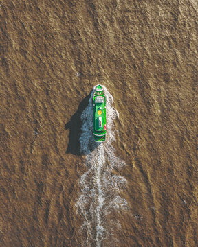 Aerial view of a bright green boat cuts through the muddy waters near Landeyjahafnarvegur, leaving a frothy white wake behind, Landeyjah&Atilde;&para;fn, Rang&Atilde;&iexcl;r&Atilde;&frac34;ing eystra, Iceland.