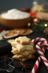Christmas composition with festive decor and cookies on black table, closeup