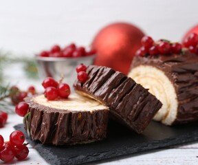 Delicious Yule log (traditional Christmas cake) with redcurrant on table, closeup