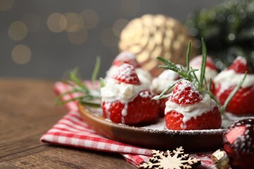 Christmas food. Santa hats made of strawberries, whipped cream, rosemary and decor on table against background with blurred lights, space for text. Bokeh effect