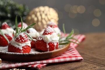 Christmas food. Santa hats made of strawberries, whipped cream, rosemary and decor on table against background with blurred lights, space for text. Bokeh effect