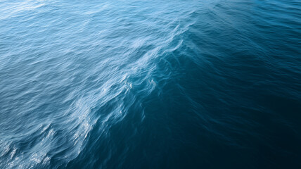 Top view endless empty ocean with gentle undulating waves, deep blue water, natural texture, peaceful and serene atmosphere, sunlight reflection