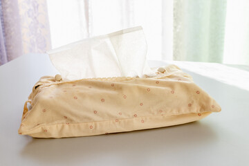 窓際の白い机の上に置かれたティッシュペーパーの箱