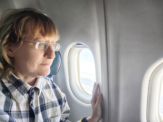 Mature woman enjoying a window seat on an airplane during a travel adventure