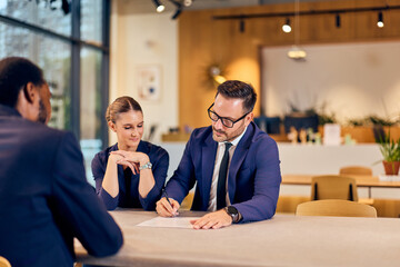 Business Meeting With Colleagues Signing Documents in a Modern Office Cafe Setting