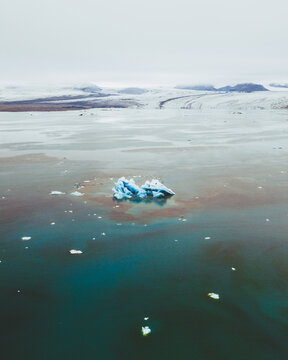 Aerial view of glacial icebergs reflecting the sky's pale hues amidst the serene, dark waters of J&Atilde;&para;kuls&Atilde;&iexcl;rl&Atilde;&sup3;n, Sveitarf&Atilde;&copy;lagi&Atilde;&deg; Hornafj&Atilde;&para;r&Atilde;&deg;ur, Iceland.