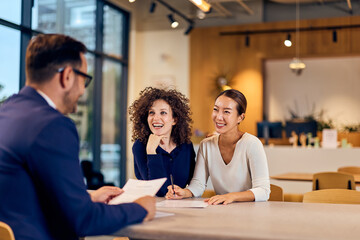 Professional Meeting in a Modern Café: Two Women Discuss Documents with a Man