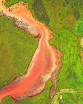 Aerial view of a vibrant, salmon-colored river snaking through a verdant landscape, a striking contrast of hues creating a surreal, painterly effect, Hv&Atilde;&shy;t&Atilde;&iexcl;, Iceland.