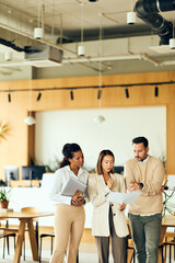 African-american Woman, Asian Woman, and Man Collaborate in Modern Office Meeting Over Documents