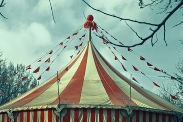Big top circus tent with red and white stripes and flags waving in the wind