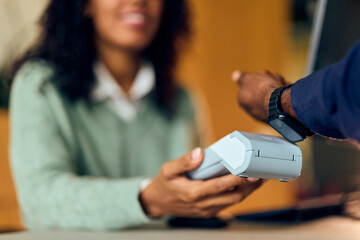 African-American Woman In Green Sweater Receives Card Payment From Person With Smartwatch During...