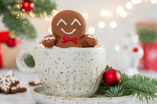 A gingerbread man is sitting in a cup of hot chocolate