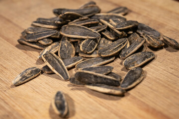 A small pile of striped sunflower seeds rests on a warm wooden board, showcasing natural texture and earthy tones.