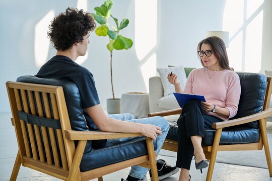 Middle aged female professional mental therapist working with young male patient