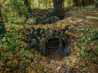 The moss-covered entrance of the Vidróczky Cave lies hidden under a carpet of colorful autumn leaves in the Bükk Mountains, Hungary.