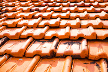 old roof tiles. Vintage abandoned damaged house roof with square hole in ceiling overlooking cloudy sky. Collapsed concrete wall with hole in abandoned industrial or residential building, close up