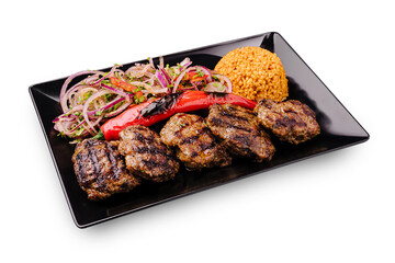 Grilled kebabs served with rice and salad on a black plate