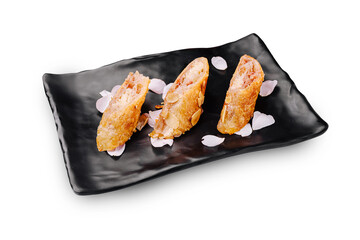 Delicate spring rolls served on a black plate with flower petals