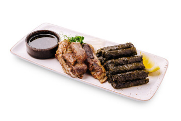 Delicious plate of grilled meat and stuffed grape leaves served with sauce