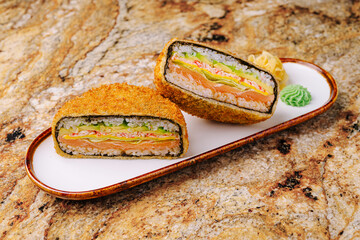 Delicious sushi sandwich cut in half on a decorative white plate
