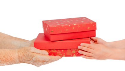 Elderly and young hands exchanging red gift boxes with golden decoration, isolated on white background. Symbolic image of giving, care, family connection, and Christmas generosity between generations.