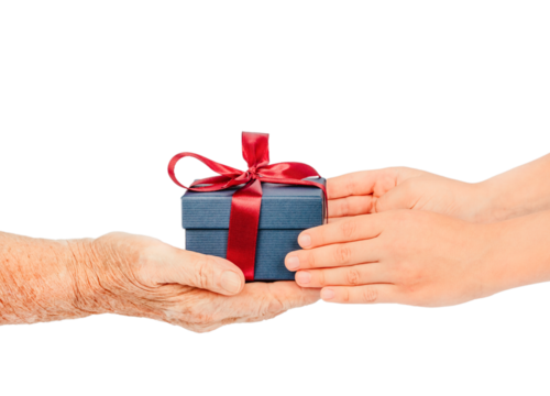Elderly and young hands exchanging a small blue gift box with a red ribbon, isolated on white. Concept of care, giving, gratitude connection between generations during holidays. special occasions.